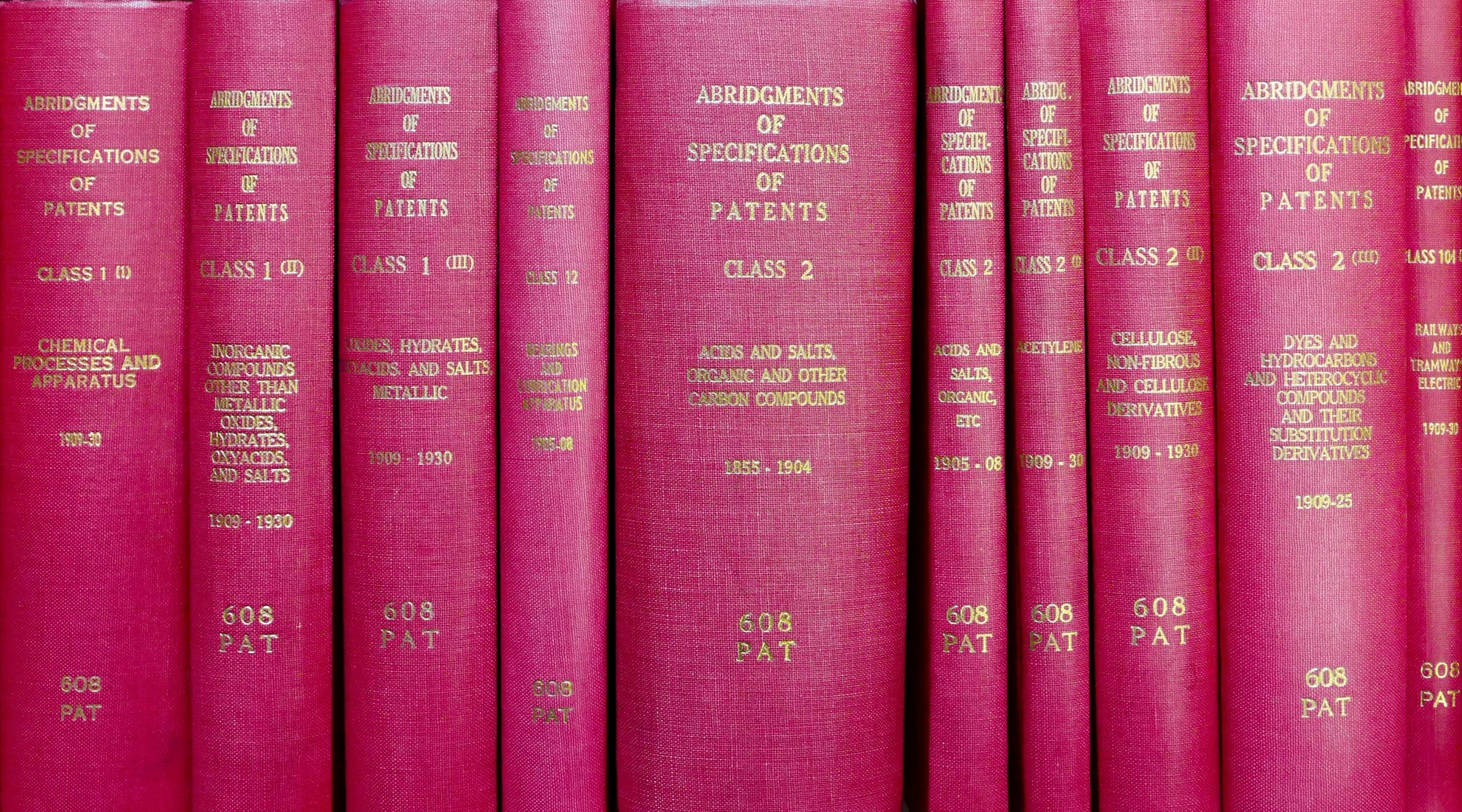 A row of red hardcover books titled 'Abridgments of Specifications of Patents'.